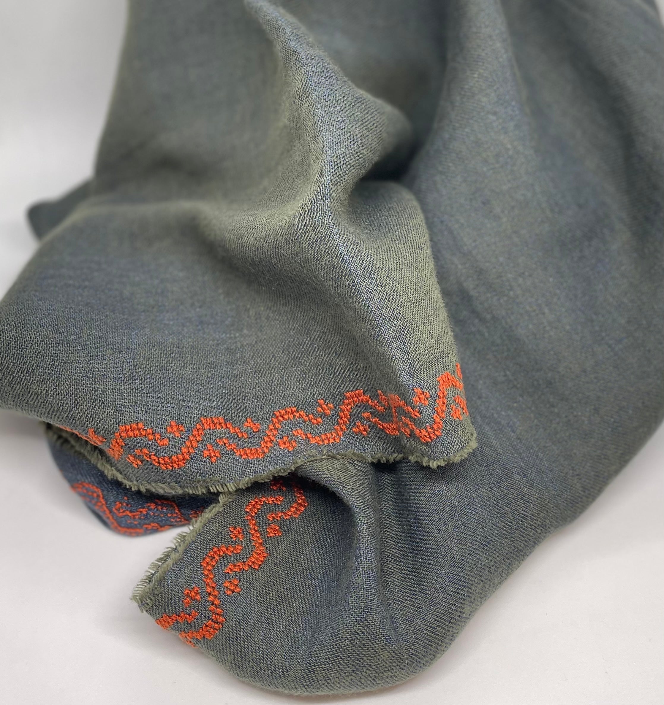 Khaki linen shawl with copper wave embroidery, draped elegantly