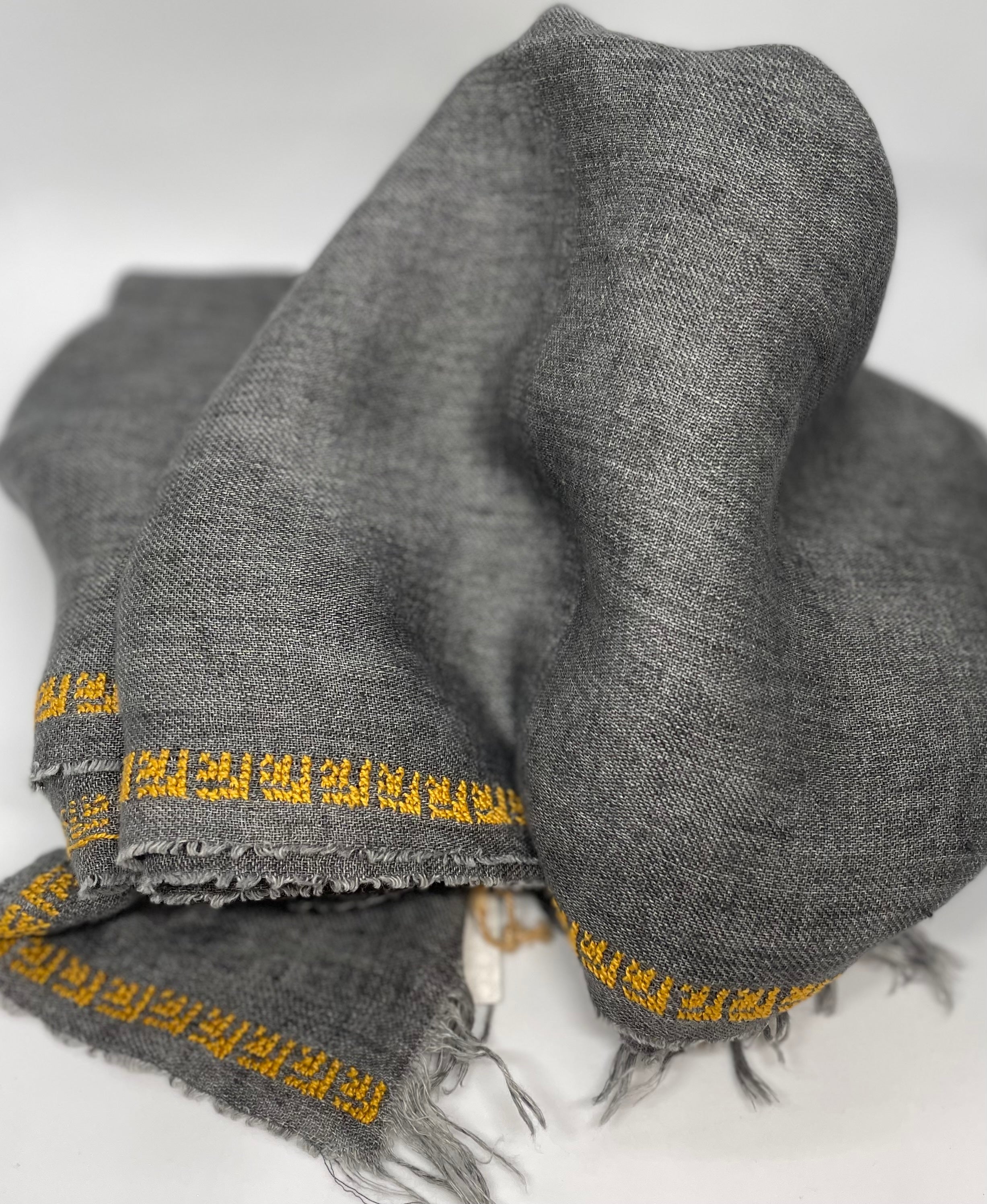 Grey linen shawl featuring a hand-embroidered rose pattern, crafted in Italy and Jordan.