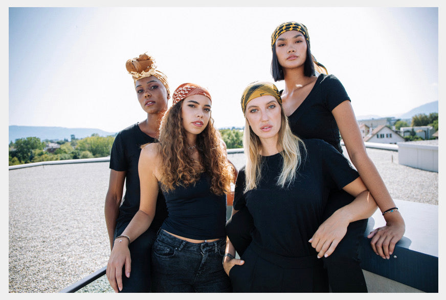 Four women posing together outdoors with a scenic background