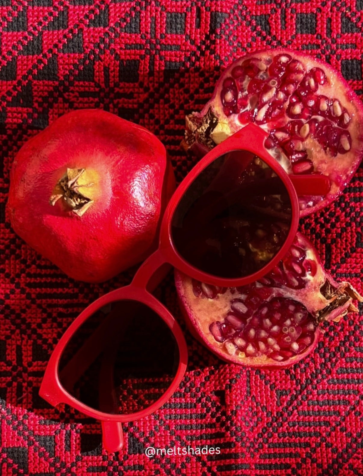 Red sunglasses with pomegranate seeds on a red patterned background