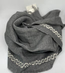 Grey linen shawl featuring ecru waves pattern, handcrafted in Italy and hand-embroidered in Jordan.