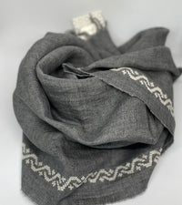 Grey linen shawl featuring ecru waves pattern, handcrafted in Italy and hand-embroidered in Jordan.
