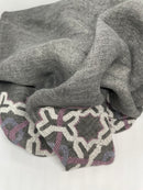 Grey linen shawl featuring a hand-embroidered lilac Alhambra® pattern, crafted in Italy and Jordan.