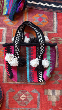 Handwoven shoulder bag crafted by Bedouin artisans using recycled yarn, featuring intricate patterns and a shoulder strap.